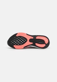 Zwarte rubberen buitenzool met roze accenten, met een gestructureerd patroon en groeven voor grip. Gepolijst ontwerp in het booggebied.