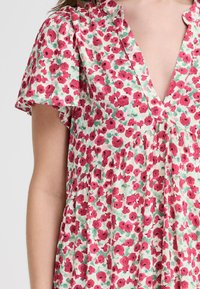 Floral dress featuring a deep V-neck, short sleeves, and a pattern of red flowers on a light green background. Soft fabric and relaxed fit.