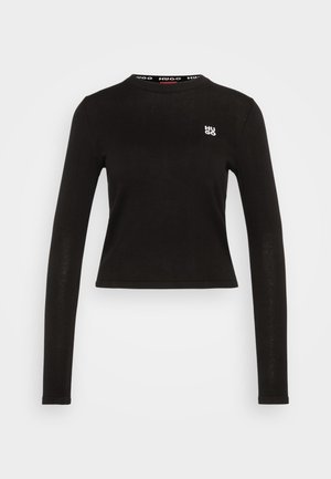 Must beežiliste varrukatega särk, mis on valmistatud ribakudumist. Omab ümarat kaelust ja valget logo vasakul rinnal. Lühendatud hemline.