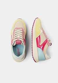 Baskets multicolores en mesh et daim. Couleurs : jaune, rose, bleu et crème avec une semelle en caoutchouc texturée.