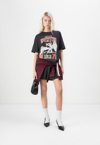 Black graphic t-shirt featuring a Led Zeppelin design, paired with a maroon sweater tied at the waist, black skater skirt, and pointed flats.