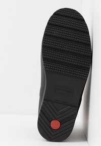 Semelle de botte en caoutchouc noir avec une bande de roulement en zigzag, logo rectangulaire "HUNTER", taille UK 4, texte "Fabriqué en Chine" et un emblème circulaire rouge près du talon.
