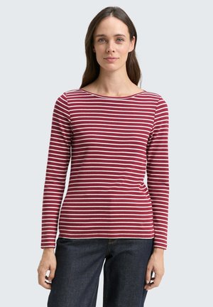 Rood-wit gestreepte langemouwtop met een bateauhals, gemaakt van een zachte stof; gecombineerd met donkere jeans.