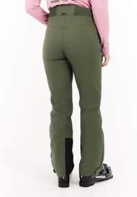 Groene technische broek met een slim fit, voorzien van een hoge tailleband en zwarte accenten bij de enkels. Gemaakt van duurzaam, flexibel materiaal.
