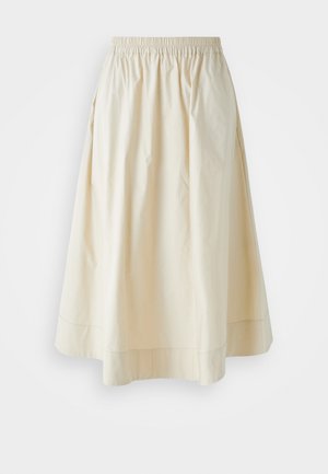 Gaiši beidzīgā, līdz ceļiem garā svārku izgatavota no gludas kokvilnas ar elastīgu jostu un nemanāmām krokām, lai pievienotu apjomu. Nav redzamu rakstu vai akcentu.