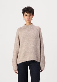 Light pink knitted sweater with a high neck, loose fit, and ribbed cuffs. The texture is soft and slightly fluffy, featuring a relaxed design.