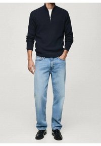 Maglione a zip color blu navy scuro, con texture a coste, abbinato a jeans a gamba dritta azzurri chiari e scarpe di pelle nere.