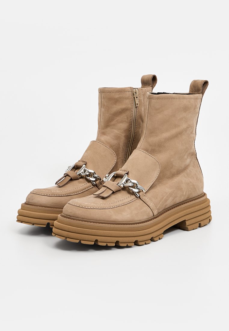 Beige Leder-Stiefeletten mit einer massiven braunen Sohle, Reißverschluss und silbernem Kettendetail, mit einer glatten Textur und abgerundeter Zehenpartie.