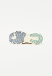 Semelle de chaussure de sport présentant un motif texturé en gris, vert clair et blanc cassé, avec des rainures de traction distinctes et une semelle intermédiaire lisse.