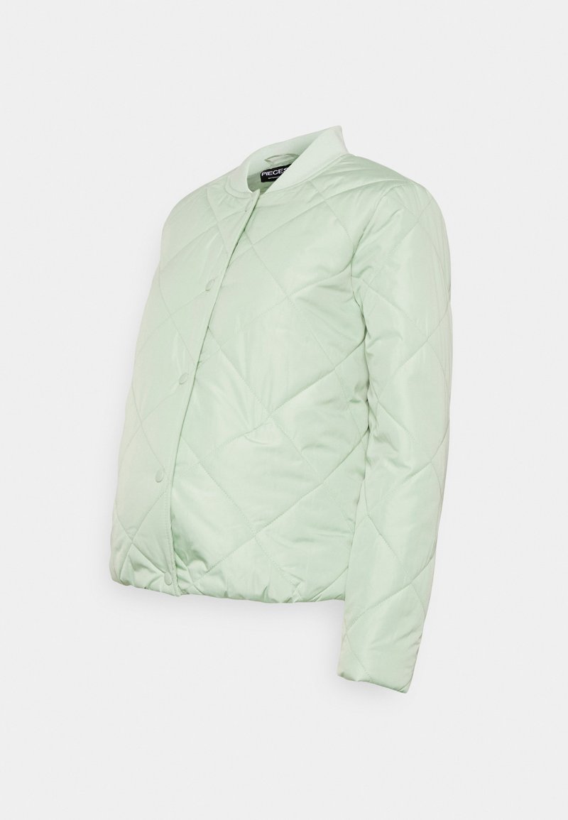 Casaco acolchoado de cor verde clara, com gola redonda e fecho de botões de pressão. O tecido possui uma textura suave e brilhante, com um design almofadado.