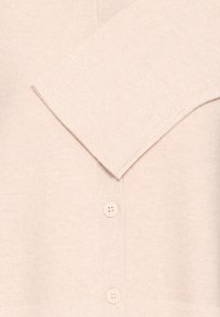 Cardigan roz pal cu textură reiată, având decolteu în V, mâneci lungi și patru nasturi asortați pe partea din față. Material moale.