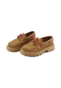 Zapatos marrones, texturizados, con un material suave y peludo. Presentan cordones rojos y una suela de goma gruesa con un perfil pronunciado. Diseño informal de tipo slip-on.