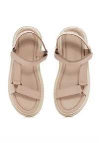 Des sandales plates beiges avec une tige en cuir, des brides réglables, une semelle intérieure rembourrée et une semelle extérieure en caoutchouc blanc texturé.