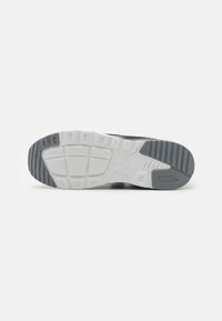 Nike-Sneakersohle mit einem strukturierten Gummidesign. Farbkombination aus Grau und Weiß, mit Rillen für Traktion und Stabilität.