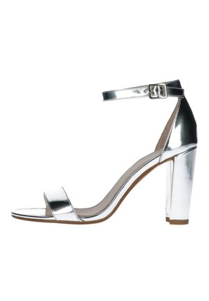 Sølv højhælede sandal med ankelrem, åben tå og en chunky hæl. Har en blank metallisk finish og et minimalistisk design.