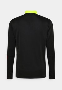 Camisa de manga larga negra con un cuello de alta visibilidad en amarillo neón y sutiles acentos rojos en los puños, fabricada con un tejido suave y ligero.