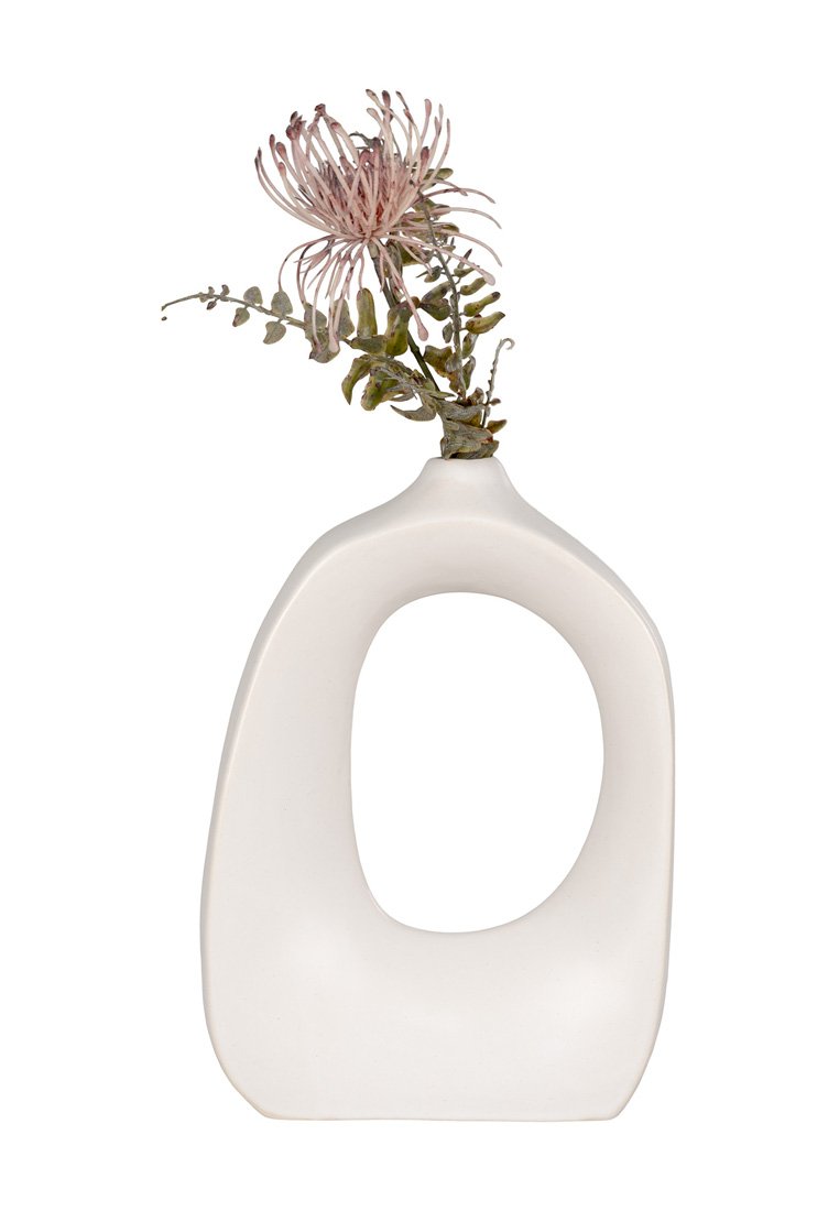 Vaso in ceramica dalla forma organica, finitura bianca opaca e un'apertura centrale. Presenta un arrangiamento di fiori finti con accenti rosa e verdi.