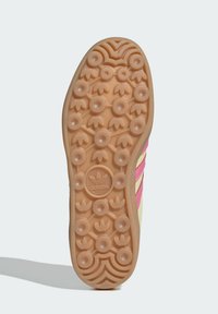 Adidas potplat tenisice od smešane gume u bež boji sa kružnim i cvjetnim uzorcima za prianjanje; sadrži ružičaste trakice i logo na peti za brendiranje.