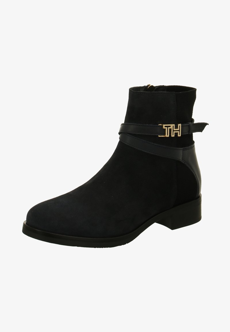 Bottine en daim noir avec talon bas, bride en cuir, panneau côtelé au talon et boucle dorée avec logo "TH" sur le côté.