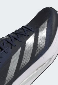 Námornícke bežecké topánky s textúrovaným zvrškom, s striebornými diagonálnymi pruhmi, zosilnenými očkami a bielou podrážkou s odpružením LIGHTSTRIKE PRO.