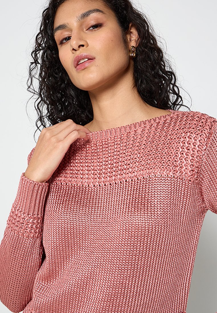 Maglione rosa lavorato a maglia con un design testurizzato, caratterizzato da un ampio scollo e polsini a costine. Il materiale sembra morbido e leggero.