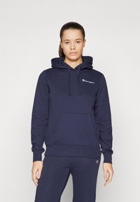 Felpa con cappuccio di cotone blu navy, dotata di una tasca frontale, polsini a costine e un piccolo logo Champion sul petto.