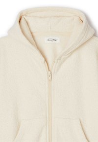 Hoodie en polaire couleur crème avec fermeture zippée intégrale, poches avant et finition douce et texturée. Comprend une capuche et une étiquette de marque discrète.