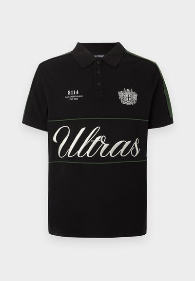 Μαύρο πόλο μπλουζάκι με πράσινες ρίγες στα μανίκια, λευκό κεντημένο κείμενο "8114 HAN KJØBENHAVN EST 2008", έμβλημα με ασπίδα και μεγάλο κείμενο "Ultras" στο στήθος.
