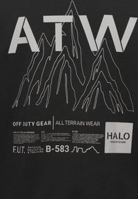 Czarna koszulka z białym napisem i grafiką gór. Wyświetla hasło "ATW OFF DUTY GEAR ALL TERRAIN WEAR" oraz dodatkowe opisy.