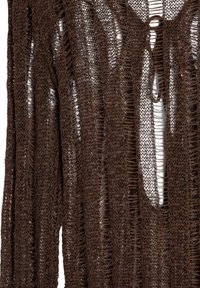 Brązowy sweter o otwartym splotce, charakteryzujący się luźnym, teksturowanym splotem z frędzlami. Projekt zawiera głęboki dekolt w kształcie V oraz nieregularne kształty.