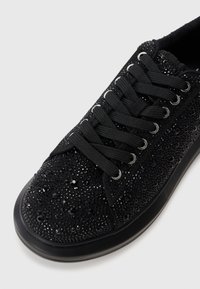 Adidași negri cu cristale strălucitoare, suprafață din material texturat, vârf rotund și talpă plată din cauciuc. Dispune de șireturi negre și bâte metalice.