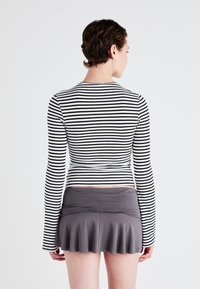 Long-sleeve top with black and white horizontal stripes, paired with a gray flared mini skirt, both made of soft, stretchy material.