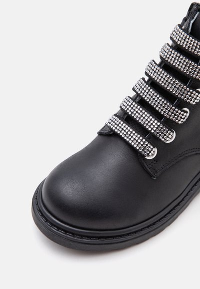 Botte en cuir noir avec un bout arrondi et plusieurs sangles décoratives recouvertes de petits clous argentés.