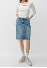 Ljusblå denimkjol i midilängd med rak skärning, fransad fåll och framfickor, kombinerad med en vit ribbad långärmad topp.