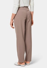 Lichtbruine, high-waisted broeken met een losse pasvorm. Glad oppervlak, minimale naden en ontworpen met riemlussen. Draag ze met witte instappers.