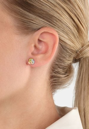 Pendientes de metal en oro, plata y oro rosa con un diseño de espiral, que presentan texturas suaves y formas redondeadas.