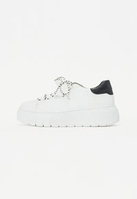 Sneaker bianco in pelle con suola spessa, accentuazione nera sul tallone e lacci a fantasia bianco e nero. Presenta una superficie liscia e dettagli di cucitura.