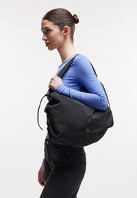 Schwarzer Rucksack aus strukturiertem Material mit einem lässigen Design, ausgestattet mit einem Kordelzugverschluss und einem verstellbaren Träger.