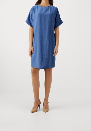 Niebieska sukienka typu shift z krótkim rękawem, wykonana z teksturowanej tkaniny, o luźnym kroju i zaokrąglonym dekolcie. Stylizowana z cielistymi szpilkami.