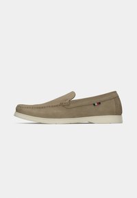 Beige suede slip-on shoe with classic moccasin stitching, flat white rubber sole, and a small accent detail in red, white, and blue.
