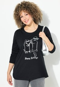 Schwarzes Langarm-T-Shirt mit einem weißen Grafikdesign von zwei Lamas mit Hüten und dem Text "Frohe Feiertage" darunter. Weicher Stoff und lockere Passform.