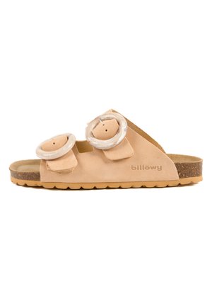 Sandale beige avec deux éléments décoratifs circulaires, en matériau suede doux, semelle en liège, design à bout ouvert et caractéristiques de sangle ajustable.