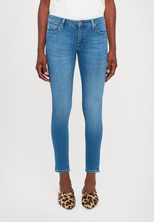Jean skinny bleu avec un lavage moyen, design à cinq poches et taille mi-haute. Présente un léger délavage et des coutures blanches au niveau de l'ourlet.