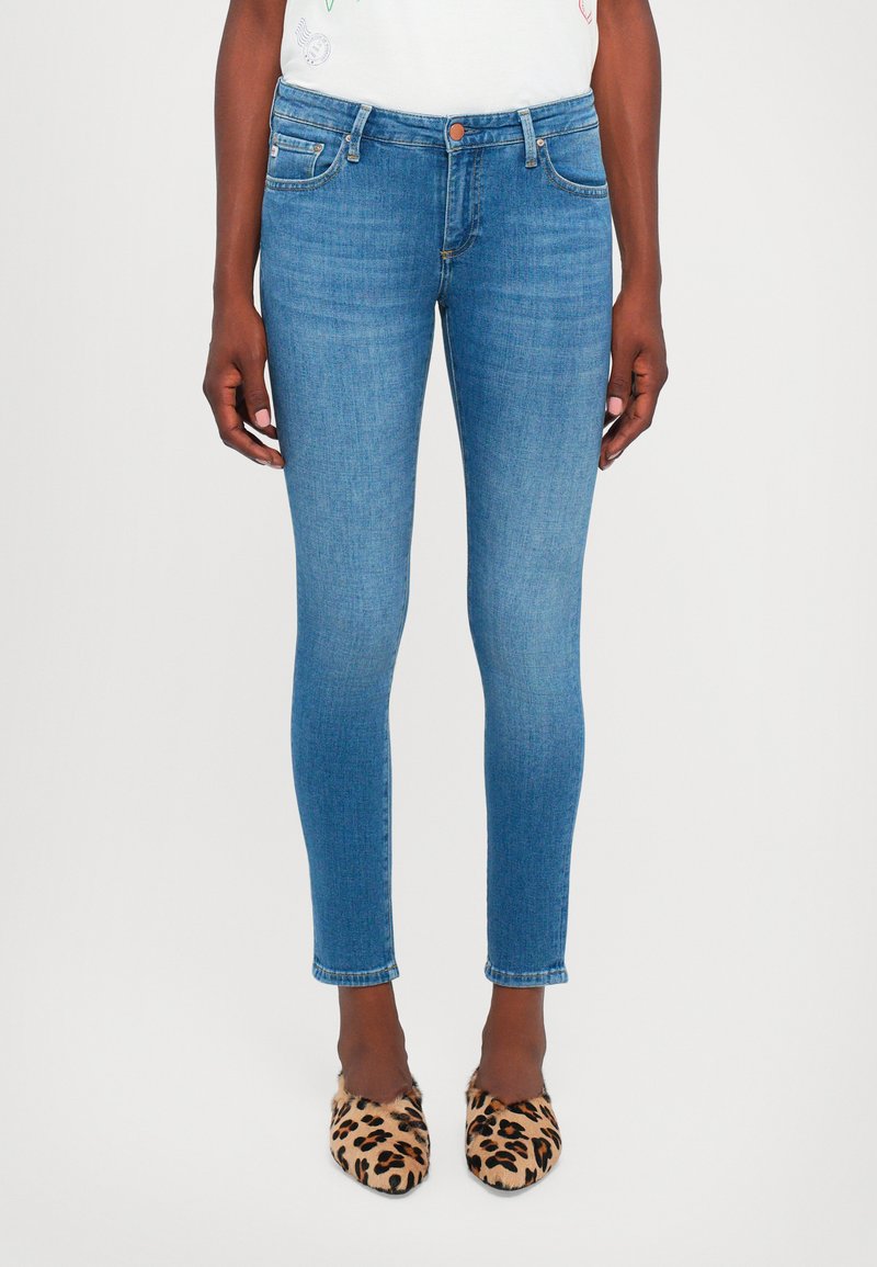 Blå skinny jeans med medelblå tvätt, femfickorsdesign och medelhög midja. Har subtila blekningar och vit söm vid fållen.