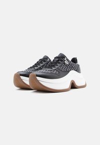 Αθλητικά παπούτσια ασπρόμαυρα με υφή στο πάνω μέρος με τρουκς, παχύ λευκό ενδιάμεσο πέλμα και ταμπά λαστιχένια σόλα.