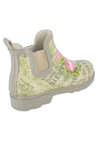 Botte de pluie à motifs floraux en vert clair avec des accents roses. Comprend une poignée, un panneau latéral élastique et une semelle en caoutchouc texturée.