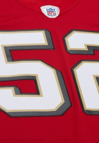 Maillot de sport rouge avec un grand numéro blanc « 56 » souligné en or et gris, avec une étiquette du logo NFL au niveau du col.