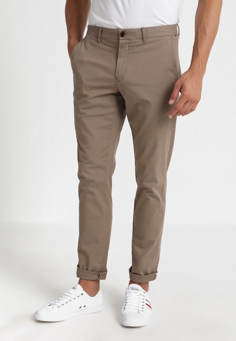 Khaki chinos o tapered fit, wykonane z bawełnianej tkaniny. Mają guzikowy zamek, przednie kieszenie i mankiety wywinięte. W połączeniu z białymi trampkami.