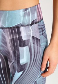 Leggings de cintura alta con un patrón geométrico multicolor, que cuentan con una tela suave y elástica y una banda elástica negra, marcados "VENICE BEACH."