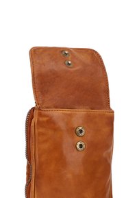 Bolso de cuero marrón con una textura suave, que presenta herrajes de latón, un cierre de cremallera en el lateral y dos broches a presión en la solapa superior.